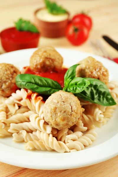 Pasta con albóndigas en plato, sobre fondo de mesa de madera — Foto de Stock