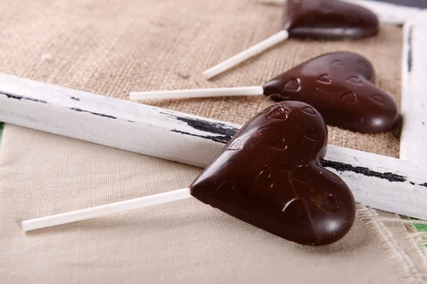 Schokolade herzförmige Bonbons auf Stöcken auf Sacktuch, Nahaufnahme — Stockfoto