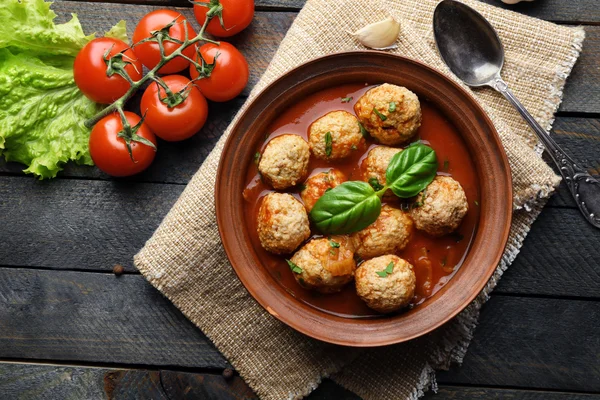 Fleischbällchen mit Tomatensauce, Holzlöffel auf hölzernem Hintergrund — Stockfoto