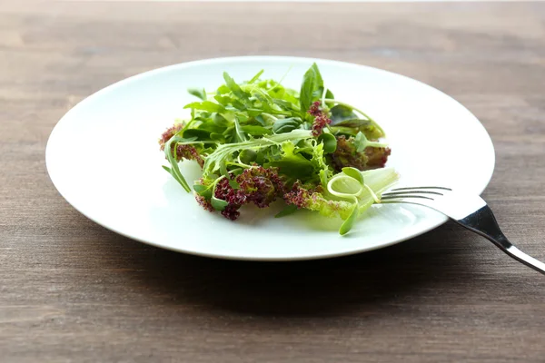 Ahşap masa üzerinde taze karışık yeşil salata tabak kapat — Stok fotoğraf