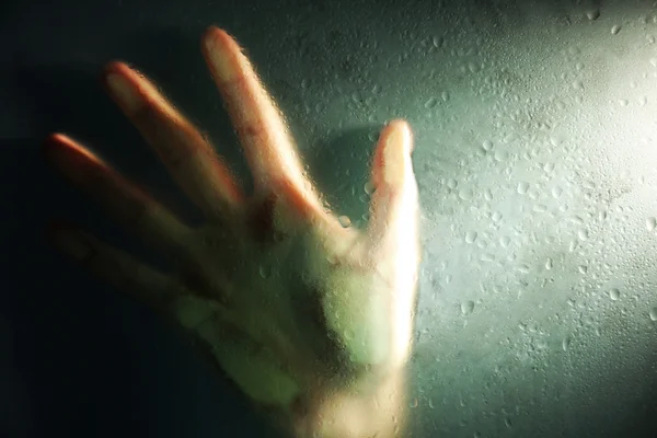 Female hand behind  wet glass — Stock Photo, Image