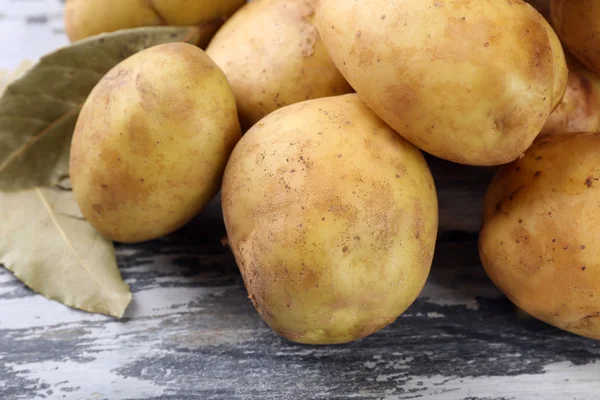 Batatas jovens com folhas de louro na mesa de madeira perto — Fotografia de Stock