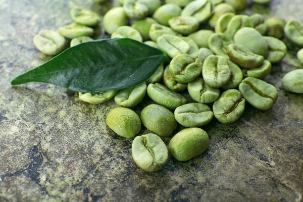 Tas de grains de café vert avec feuille sur la table gros plan — Photo