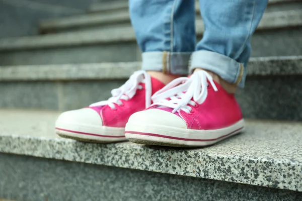 Vrouwelijke voeten in roze gumshoes op stenen trappen — Stockfoto