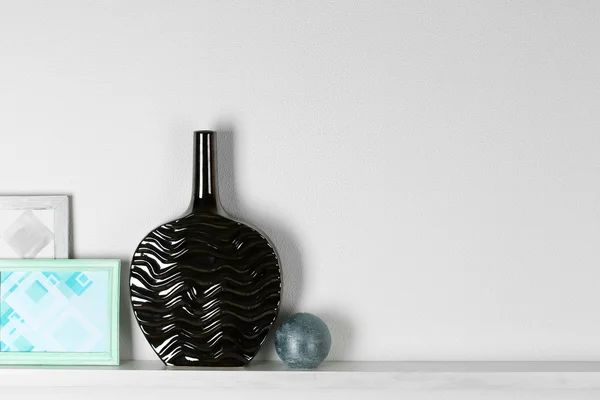 Modern vase with picture on shelf in room — Stock Photo, Image