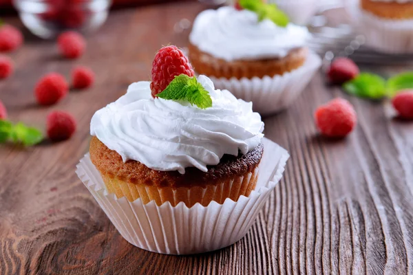 Delicious cupcakes with berries and fresh mint on wooden table close up — Stock Photo, Image