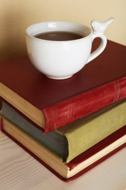 Bardak çay ile kitap yığını