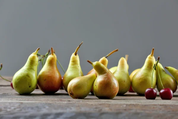 Reife Birnen und Kirschen auf grauem Hintergrund — Stockfoto