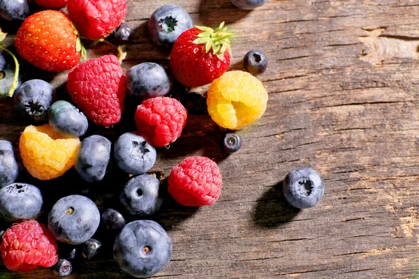 Heap of sweet tasty berries on wooden table close up — Stock Photo, Image