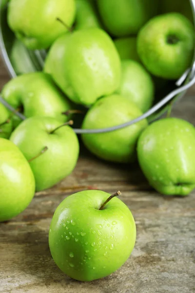 Zralé zelené jablko v plechový kbelík na dřevěný stůl zblízka — Stock fotografie