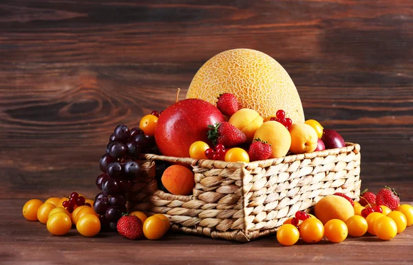 Sortidas de frutas frescas em cesta de vime no fundo de madeira — Fotografia de Stock