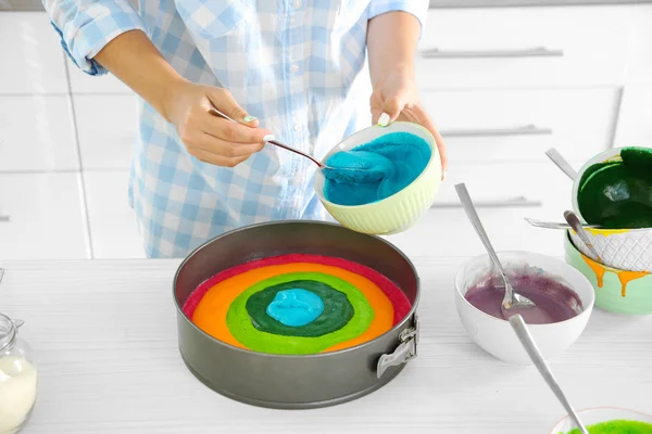 Jonge vrouw met cake van de regenboog maken in keuken — Stockfoto