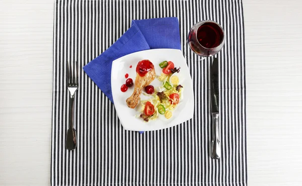 Jídlo z pečené kuřecí stehno a zeleninový salát bílá deska s sklenku vína na stole s ubrouskem, pohled shora — Stock fotografie