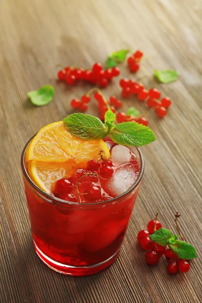 Glass of red currants juice with lemon and ice cubes on wooden table, closeup — Stock Photo, Image