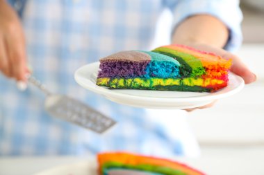 Gökkuşağı Kek kısmı ile plaka mutfakta tutan genç kadın