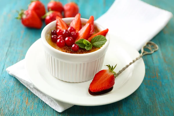 Postre de crema brulee con fresas frescas y hojas de menta, sobre fondo de madera de color —  Fotos de Stock