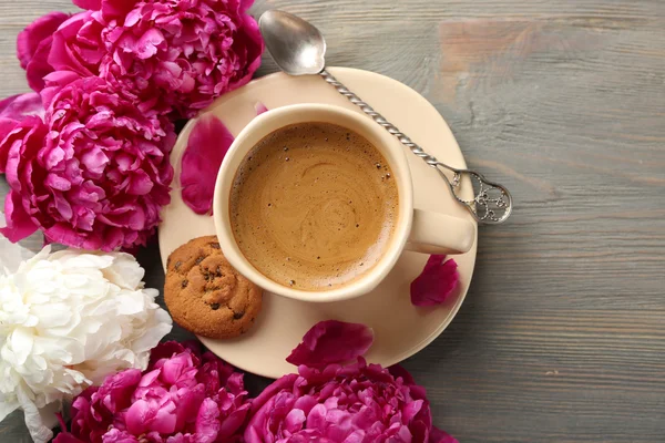 Composition avec tasse de café et de fleurs de pivoine sur fond en bois — Photo