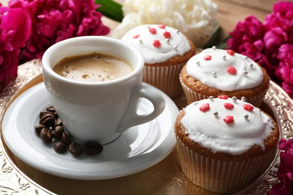 Composição com xícara de café, muffins e flores de peônia na bandeja, no fundo de madeira — Fotografia de Stock