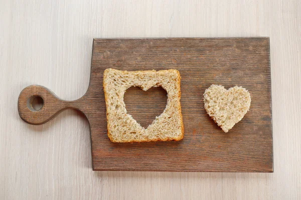 Rebanada de pan con corte en forma de corazón sobre fondo de madera — Foto de Stock