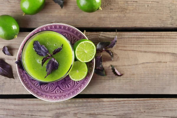 Glass of green healthy juice with basil and limes on table close up — Stock Photo, Image