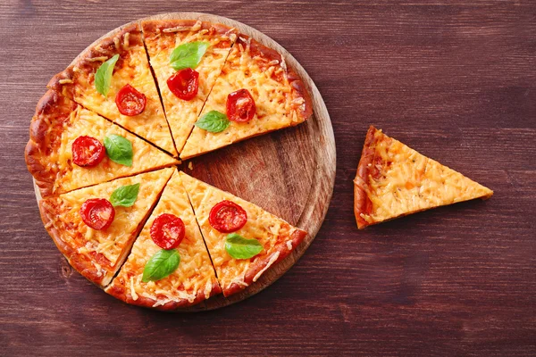 Fette di gustosa pizza al formaggio con basilico e pomodorini sul tavolo da vicino — Foto Stock