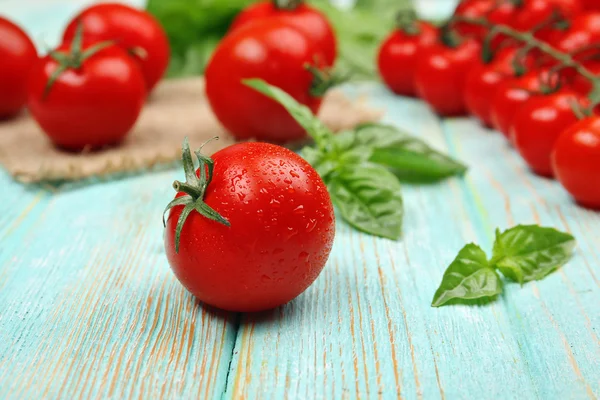 Fresh tomatoes with basil on wooden table close up — Stock Photo, Image