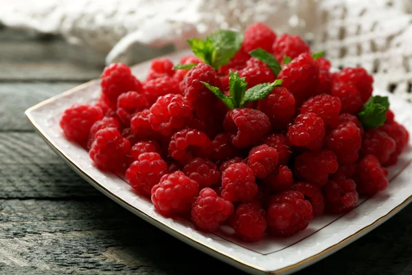 Sweet raspberries on plate on wooden  background — Stock Photo, Image