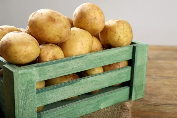 Jeunes pommes de terre en caisse sur la table fermer — Photo