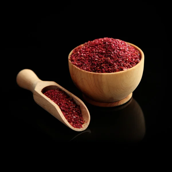 Sumac in wooden bowl, isolated on black — Stock Photo, Image