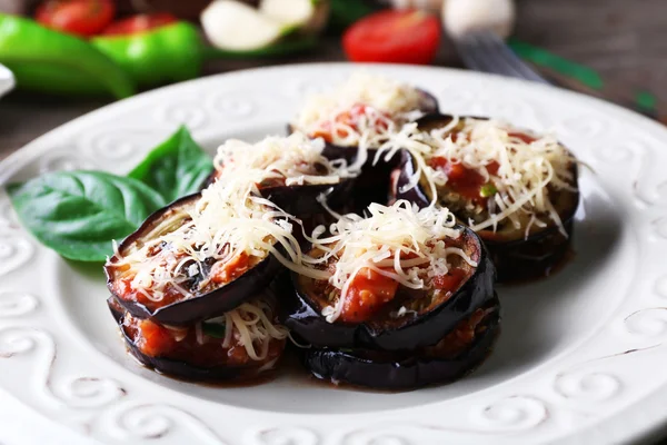 Plato de berenjena con tomates cherry y queso en plato blanco sobre mesa de madera, primer plano — Foto de Stock