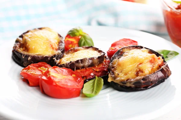 Dish of eggplant with cherry tomatoes and cheese in white plate on wooden table, closeup — Stock Photo, Image