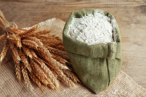 Hele bloem in jute zak met tarwe oren op houten tafel, close-up — Stockfoto