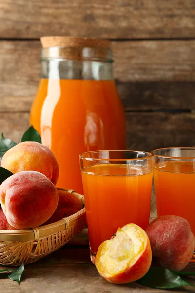 Ripe peaches and juice on wooden background — Stock Photo, Image