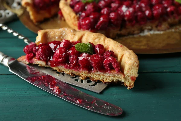 Pedaço de torta com framboesas na bandeja, close-up, na cor de fundo de madeira — Fotografia de Stock