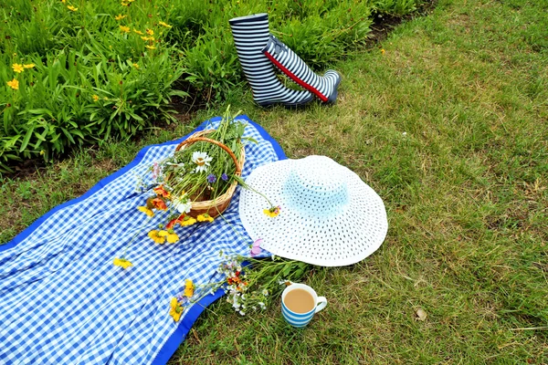 Beautiful composition with bouquet of wild flowers and rubber boots on meadow outdoors — Stock Photo, Image