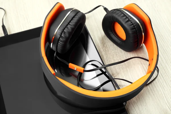 Headphones with tablet on wooden table close up — Stock Photo, Image