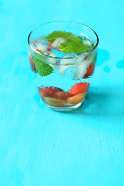 Glass of cold refreshing summer drink with berries and ice cubes on table close up — Stock Photo, Image