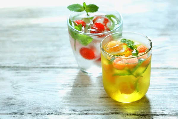 Sklenice studeného osvěžující letní nápoj s ovocem a kostky ledu na stole zblízka — Stock fotografie