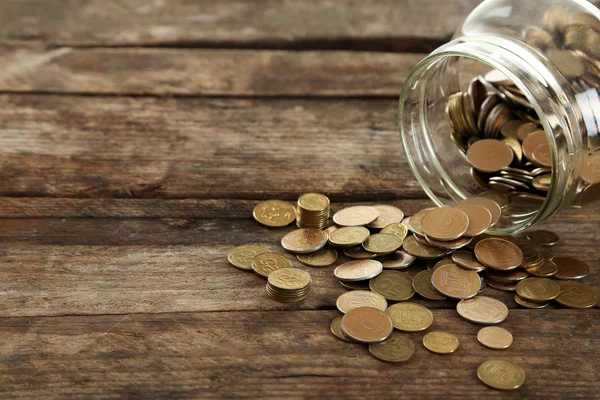 Coins in money jar on wooden background — Stock Photo, Image