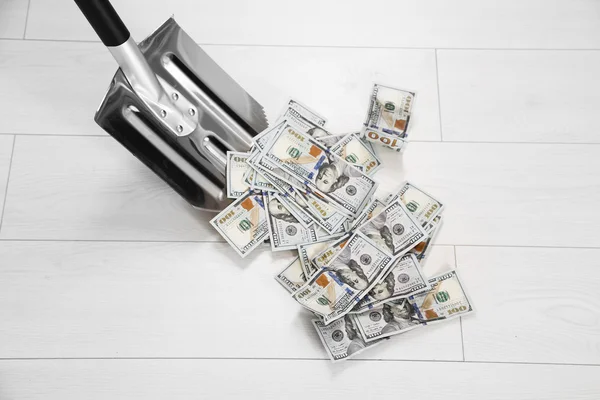 Shovel lifts dollar bills — Stock Photo, Image