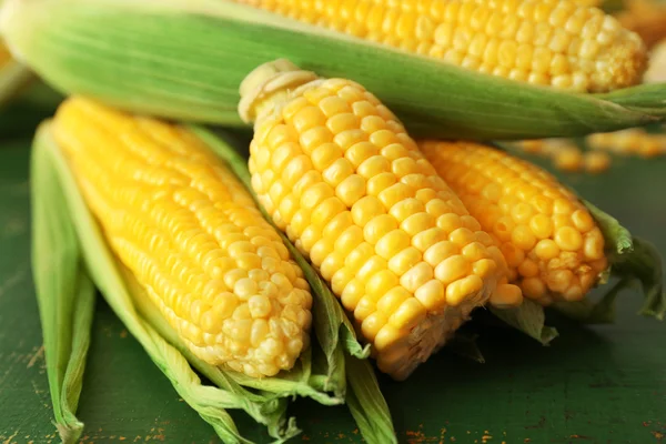 Fresh corn on cobs on green wooden table, closeup — Stock Photo, Image