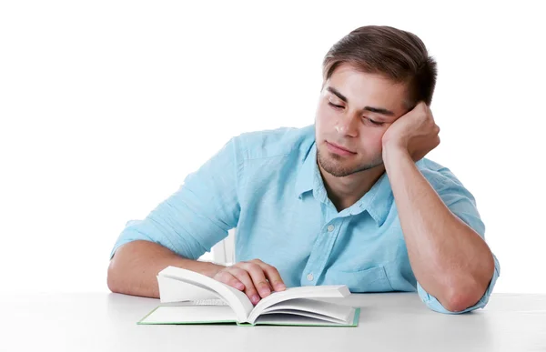 Jonge man leesboek aan tafel op witte achtergrond — Stockfoto