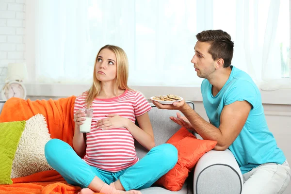 Jovem mulher grávida com marido no sofá no quarto — Fotografia de Stock