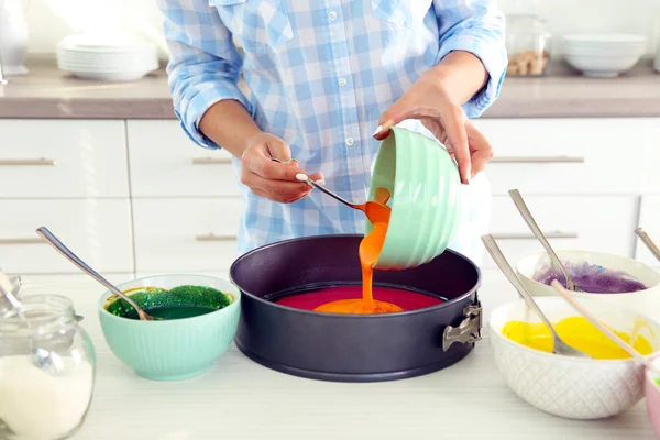 Jovem mulher fazendo bolo de arco-íris na cozinha — Fotografia de Stock
