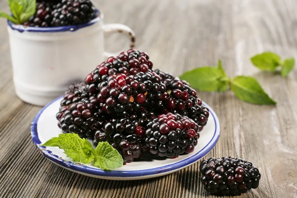 Ripe blackberries with green leaves on wooden table, closeup — Stock Photo, Image
