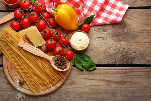 Espaguetis de pasta con tomates, queso y albahaca sobre fondo rústico de madera —  Fotos de Stock