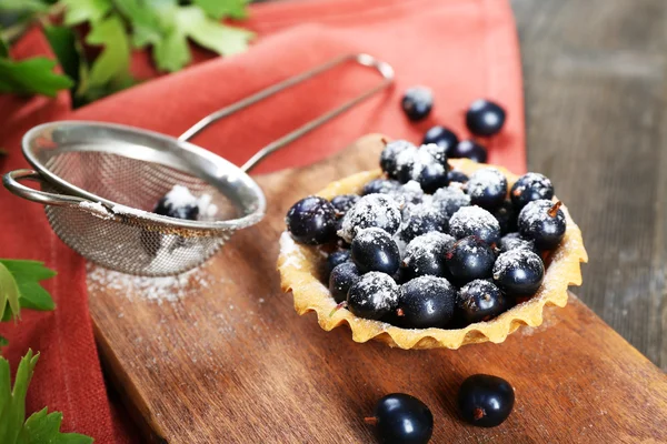 Delicious crispy tart with black currants on wooden cutting board, closeup — Stock Photo, Image