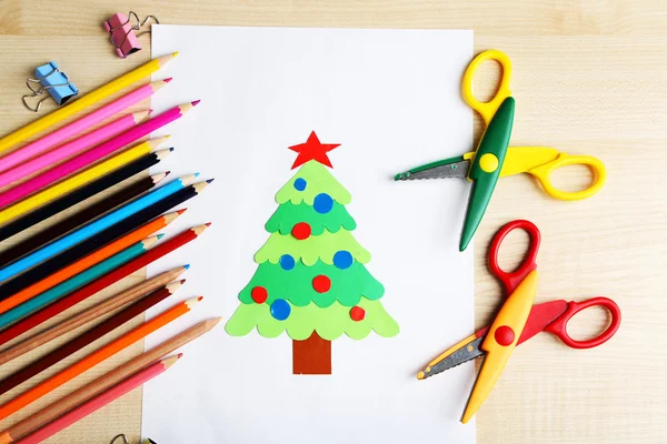 Creative paper Christmas tree on white paper sheet, scissors and colorful crayons on color table background — Stock Photo, Image