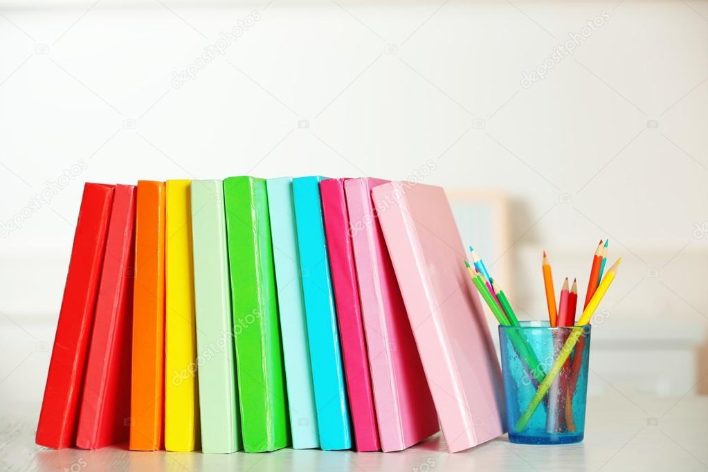 Colorful books and pencil on table in room