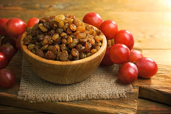 Raisins in bowl with grapes on table close up — Stock Photo, Image